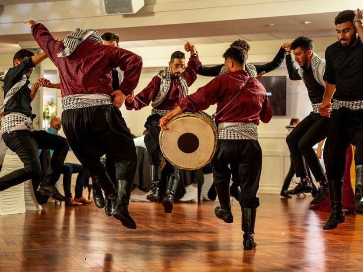 A troupe of Levantine men wearing keffiyeh scarves and performing the traditional Levantine dance known as dabkeh