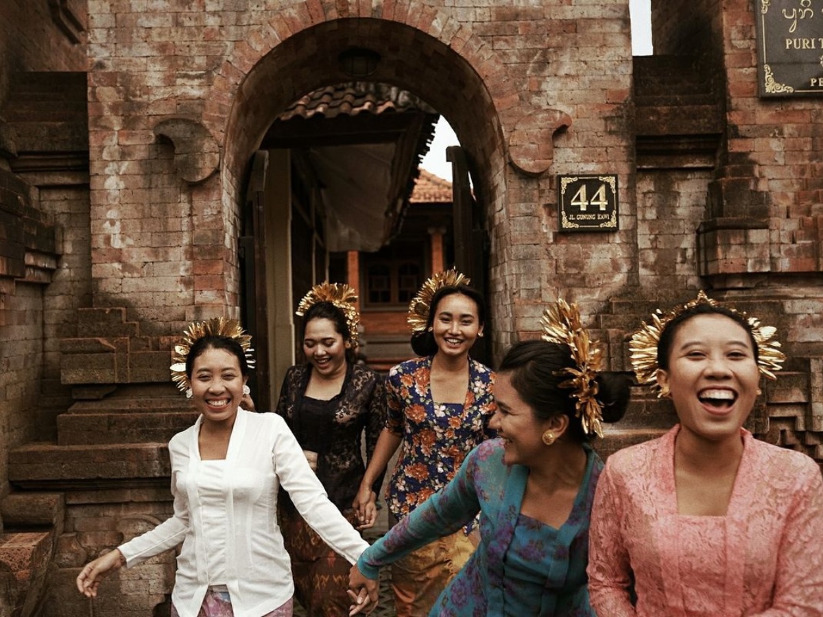 Image alt text: Balinese community of women dressed in traditional attire and running through the village