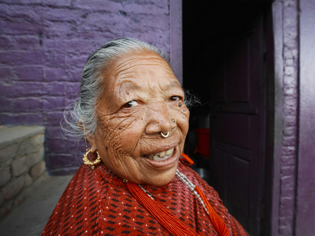 An elderly South Asian woman photographed with her ear, nose, and septum pierces