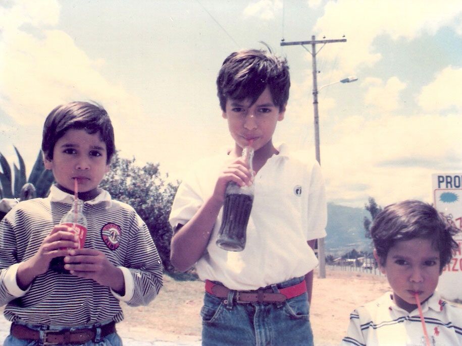Vintage photo of three children holding bottles of coca-cola, symbolizing adaptation to western culture