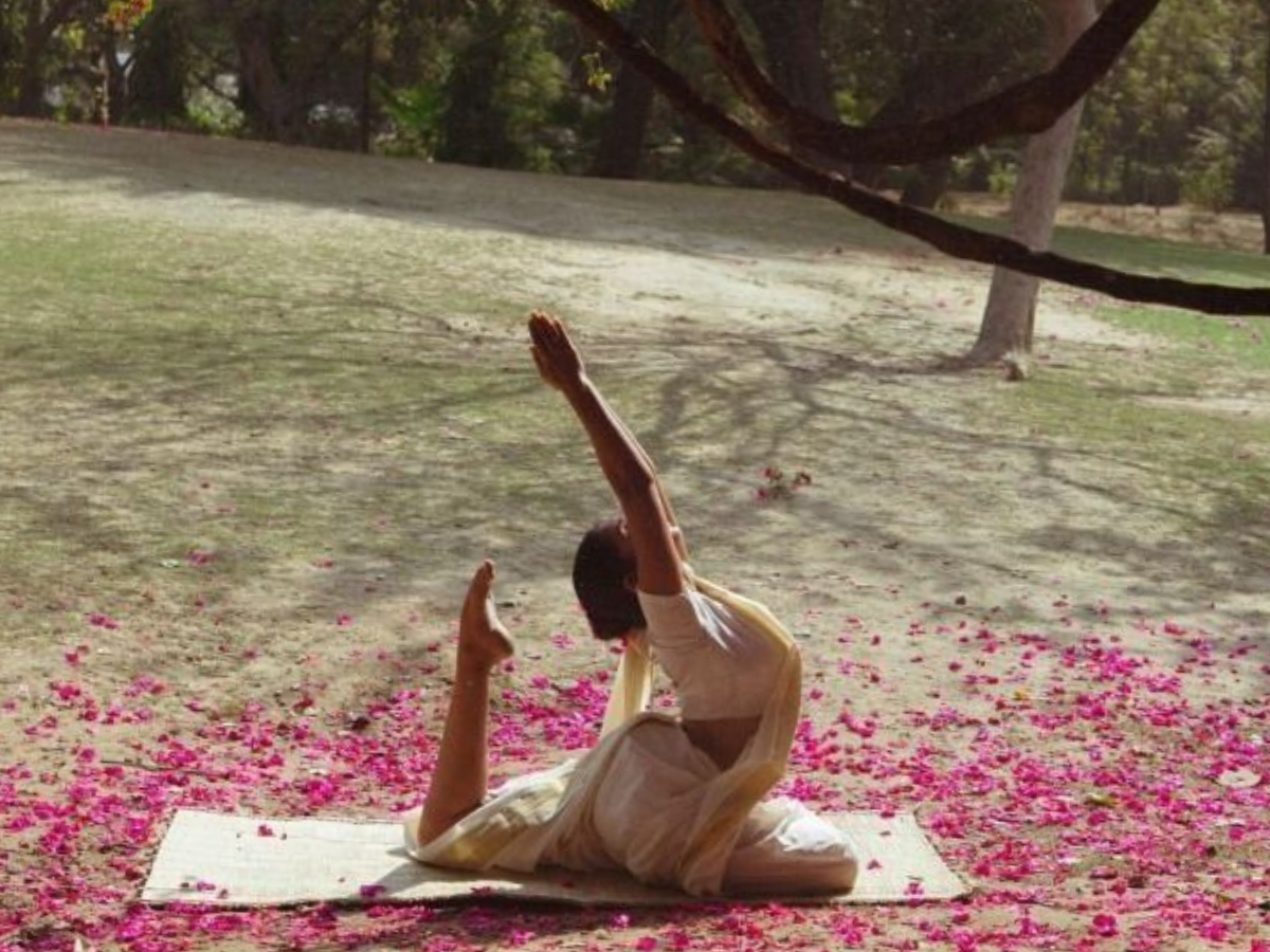 A yoga practitioner demonstrating a backbending yoga asana in a garden